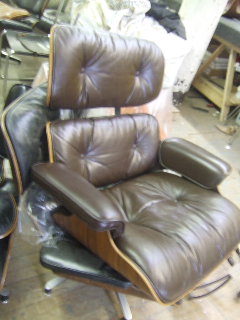 Eames lounge chair with brown leather cushions after reupholstery in the shop