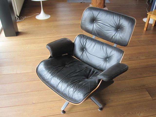 Eames lounge chair with black leather cushions on a wood floor