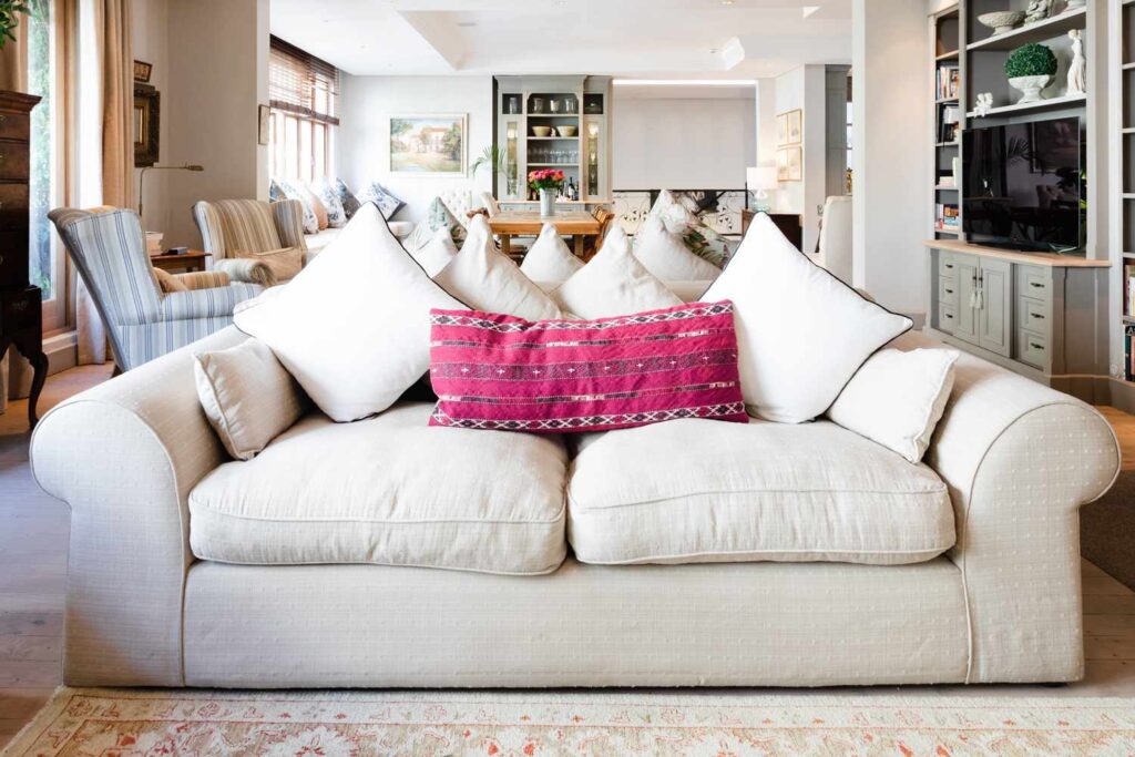 Cream upholstered sofa with loose cushions in a bright, open living room