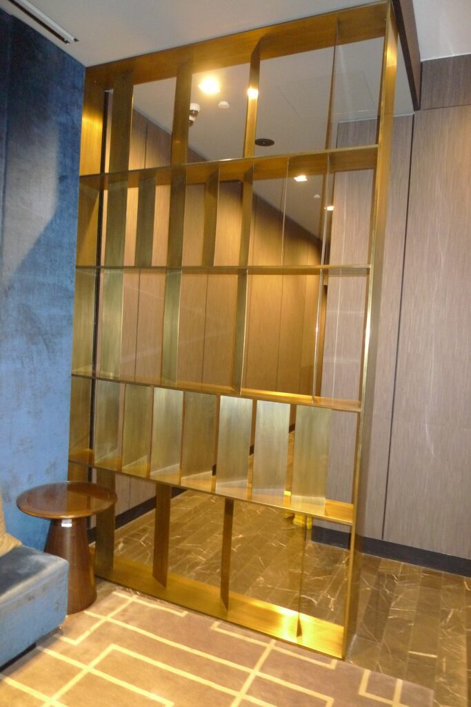 Custom brass open-grid shelving screen beside a stone-tiled floor