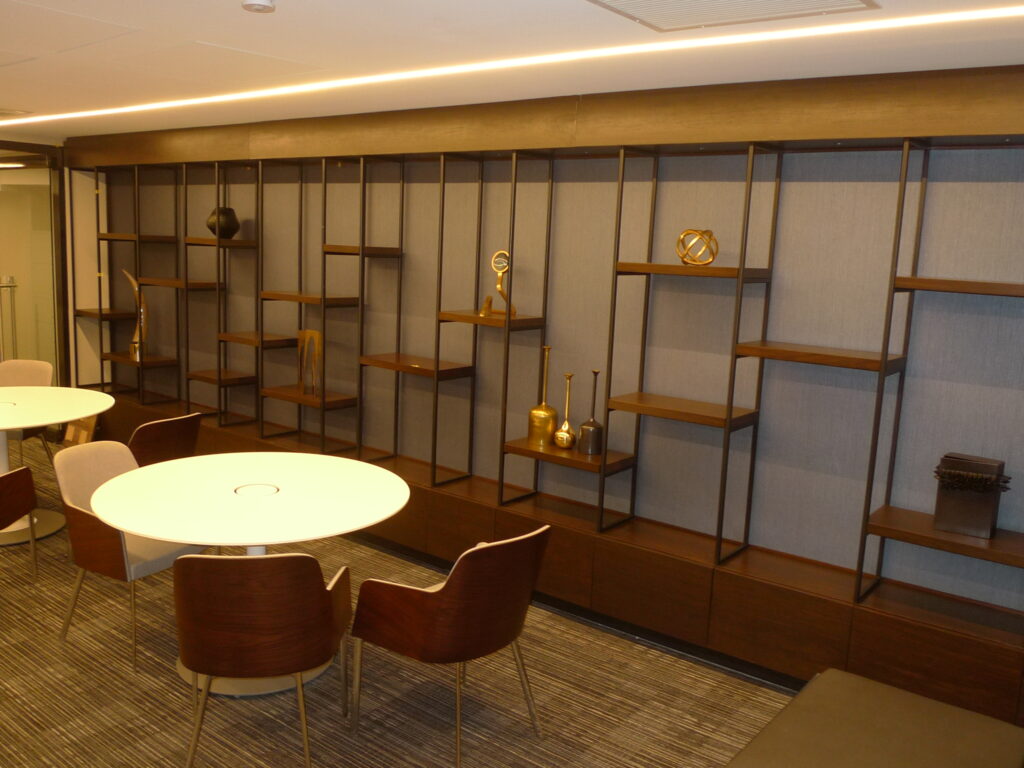 Commercial lounge with wood-shell upholstered dining chairs and custom wood and metal shelving