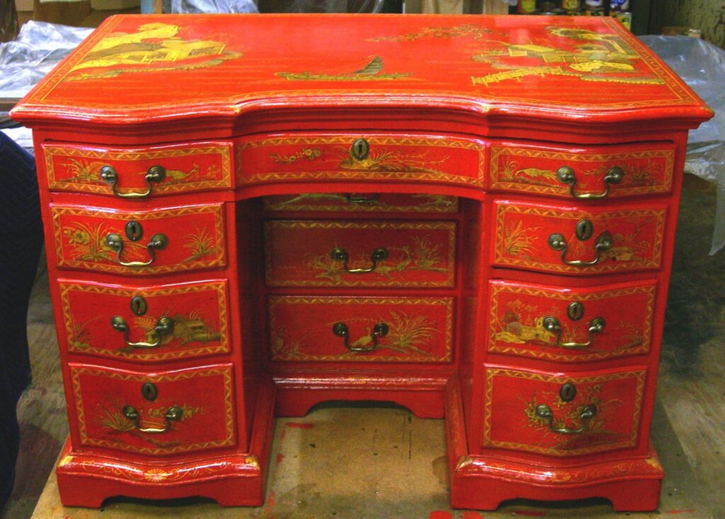 Antique red lacquer kneehole desk with gilt chinoiserie decoration and brass hardware