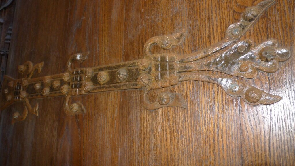 Ornate historic bronze and iron strap hinges on a restored Riverside Church wood door