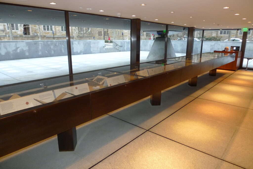 Row of long glass-topped display vitrines with wood casework at Yale Beinecke Rare Book and Manuscript Library